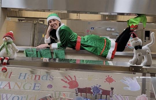 School nurse dressed as elf, poses in the cafeteria waiting for the students to find her