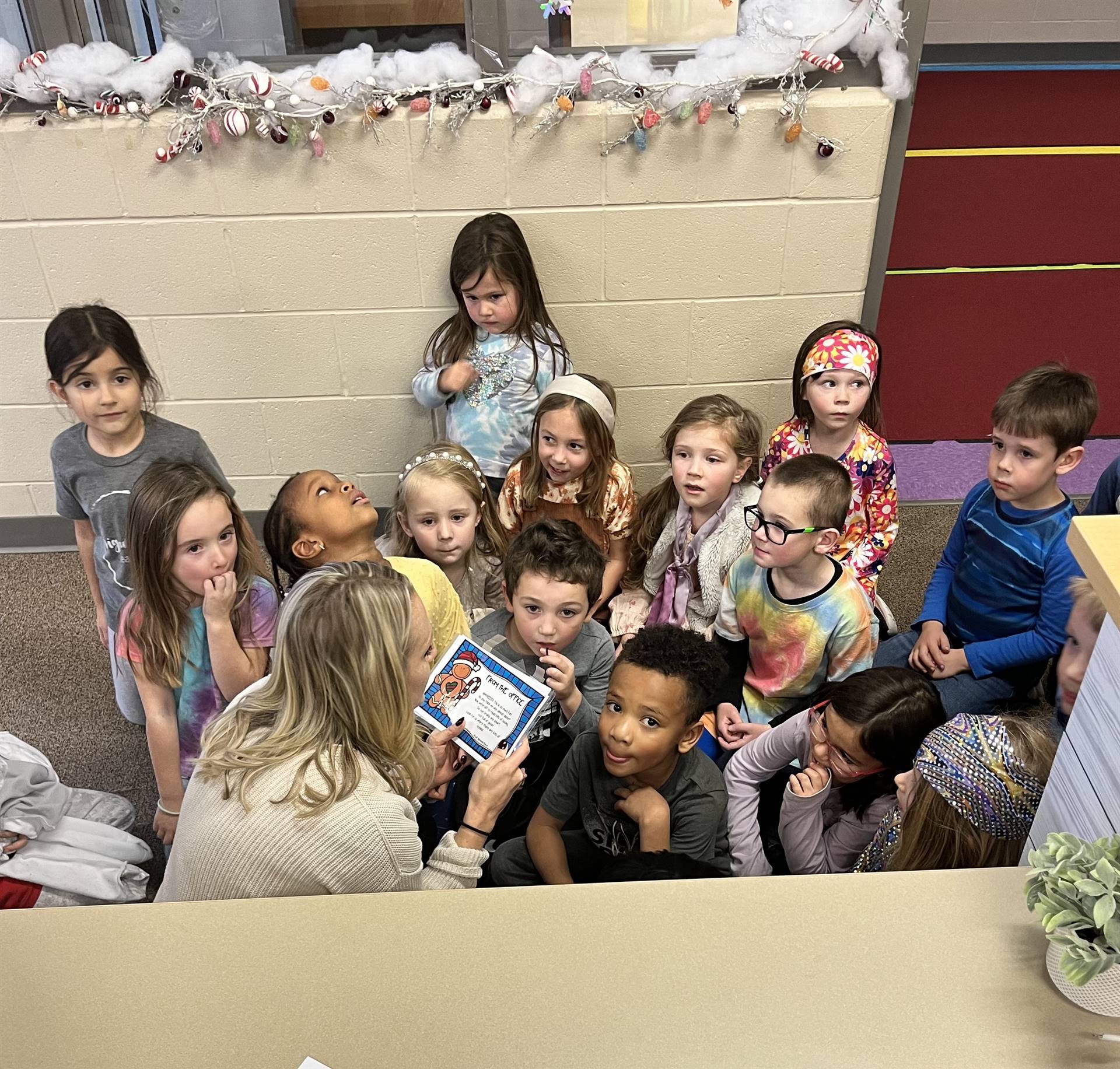 Mrs. Bresnahan and students hunt for gingerbread men around the building. they huddle to listen to t