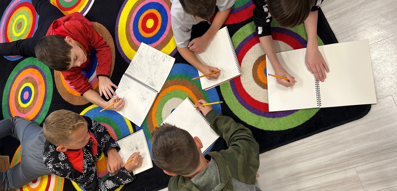 Five students working on a project laying on a rug