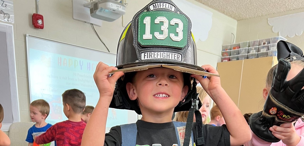 A student trying on a firefighter helmet