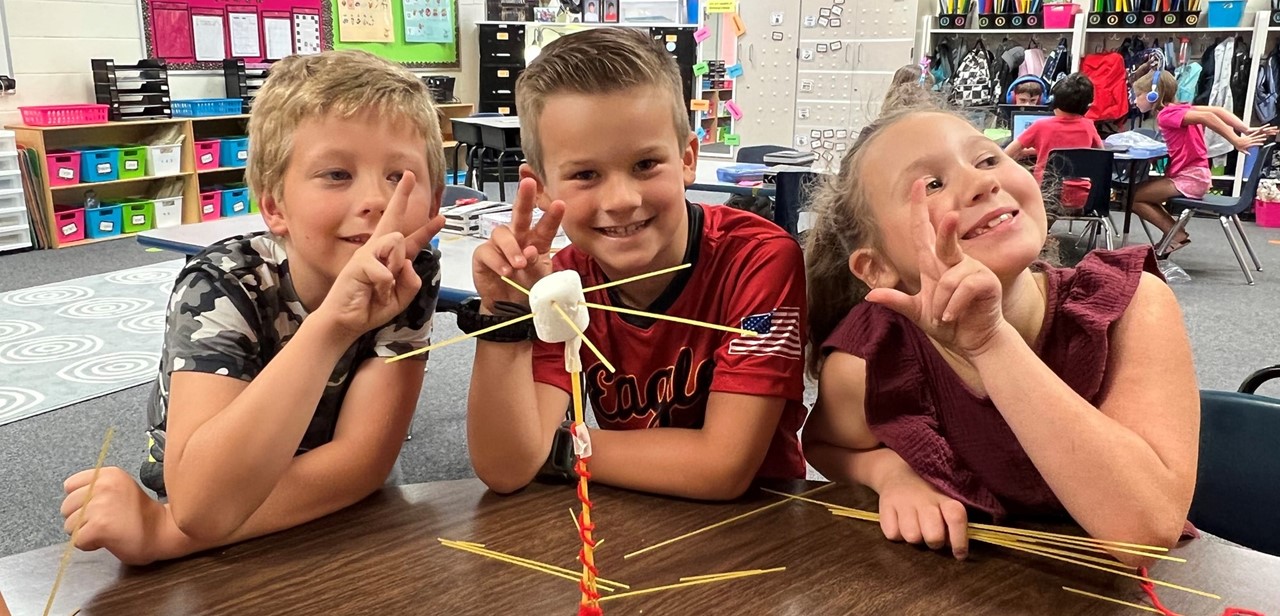 Three students building a tower out of spaghetti and marshmallows