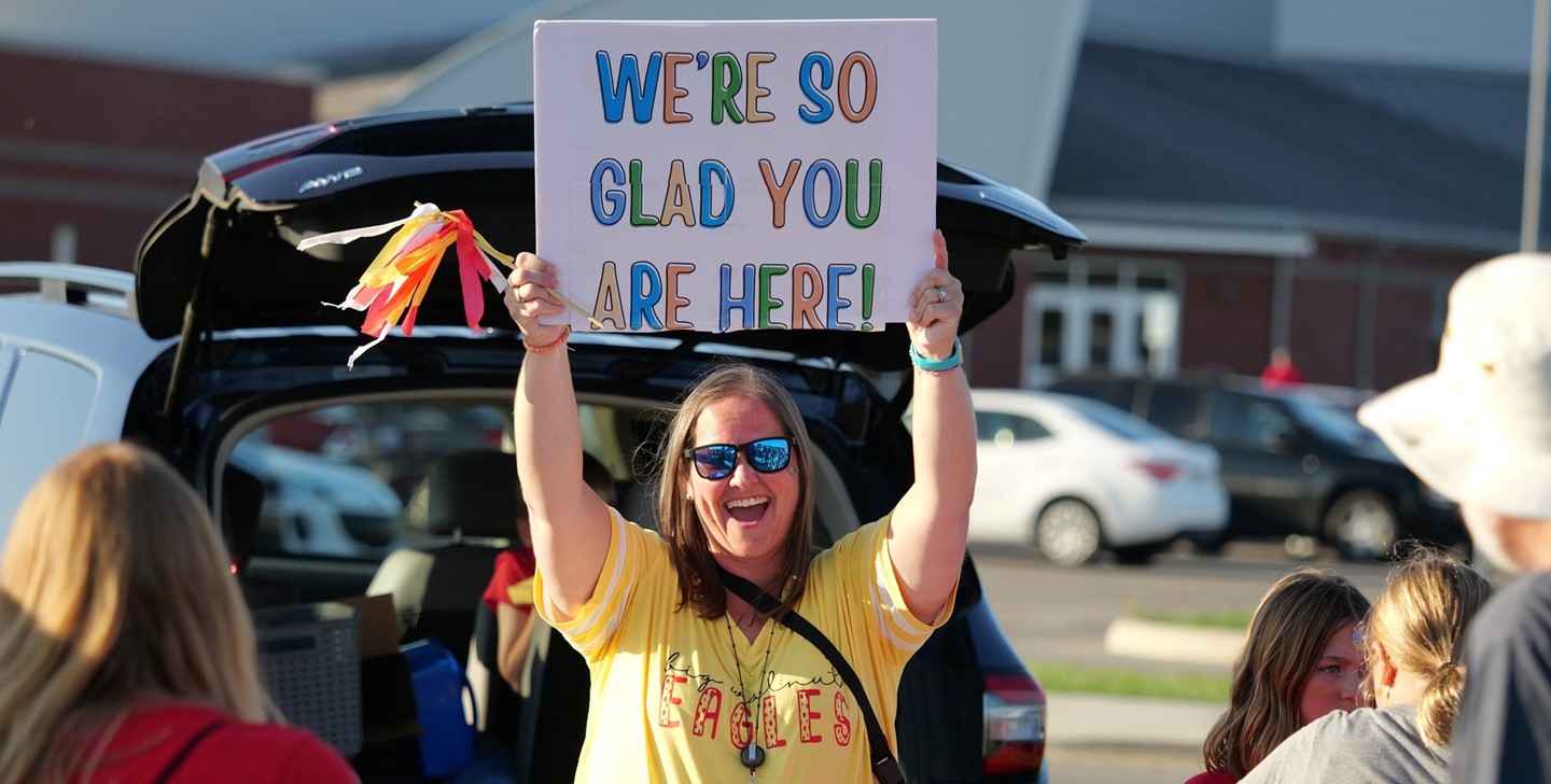 Big Walnut Intermediate School Principal Sandrock holding a sign that reads: &#34;We&#39;re so glad you are here!&#34;