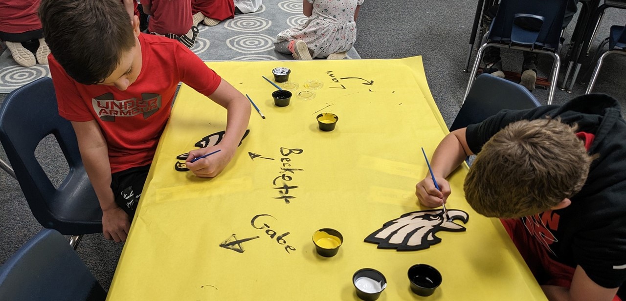 Two students painting an eagle