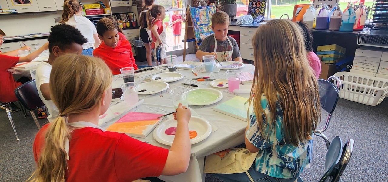 Students painting around a table