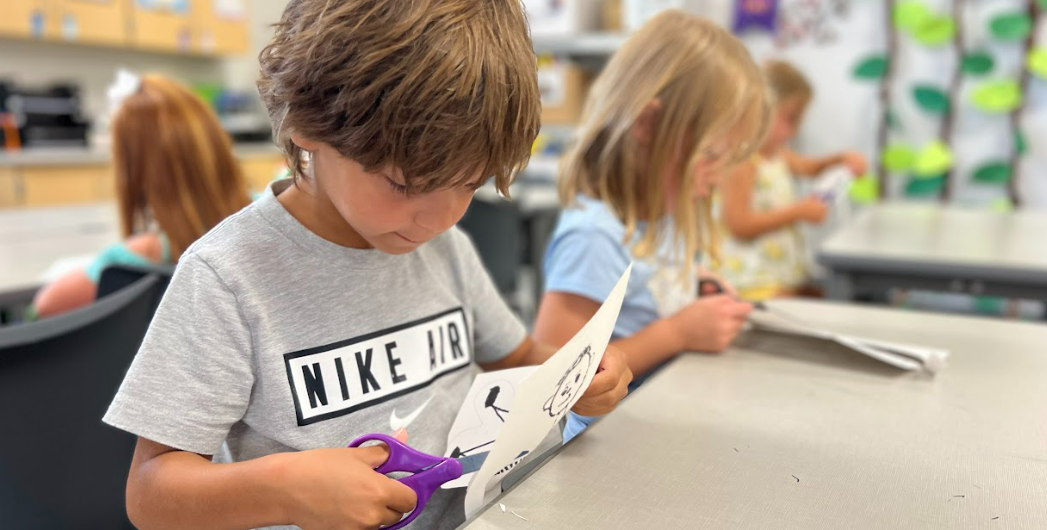 A student using scissors to create art