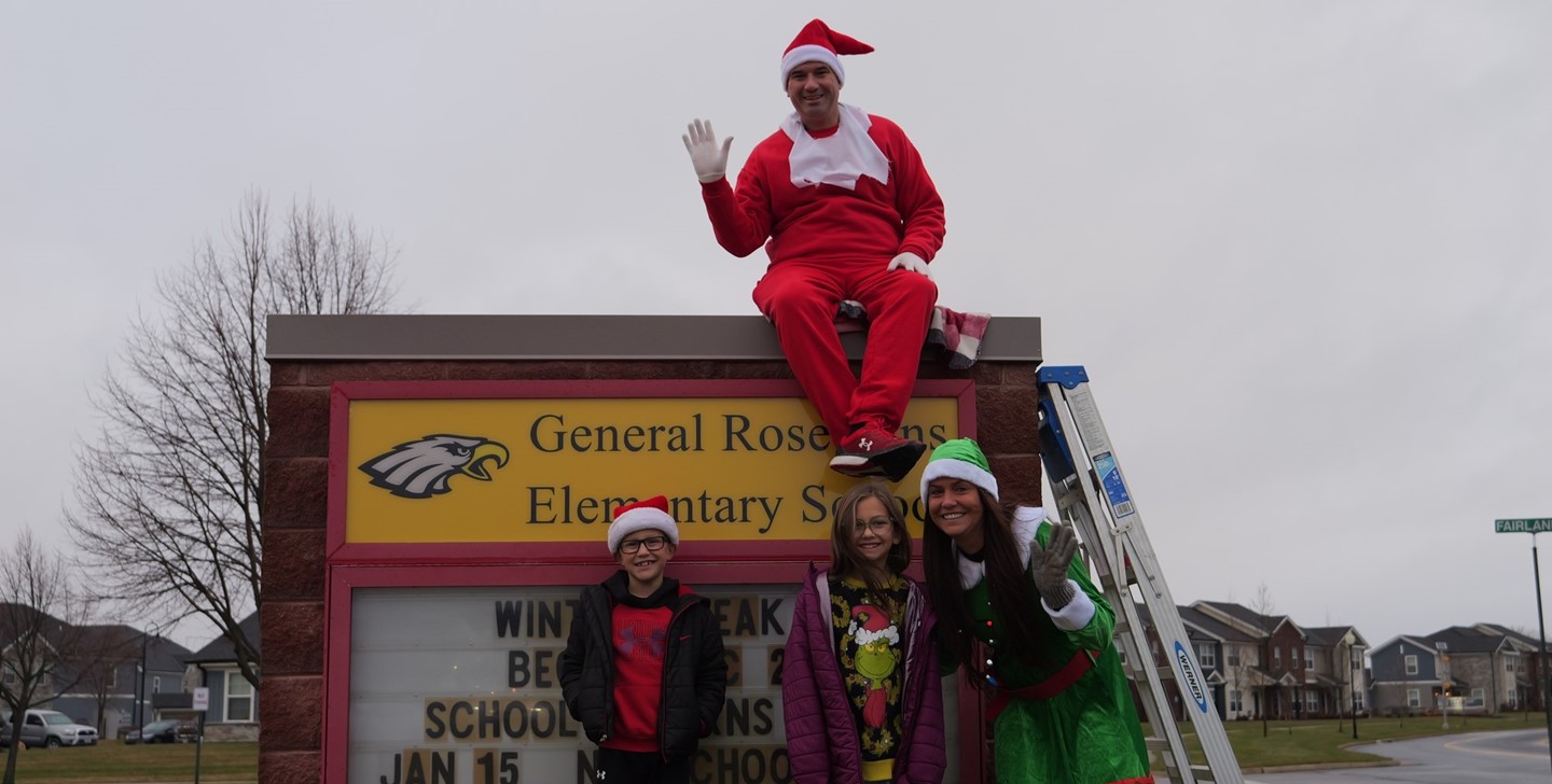 Superintendent Ryan McLane poses as an elf with Principal Crawford and students in front of General Rosecrans Elementary