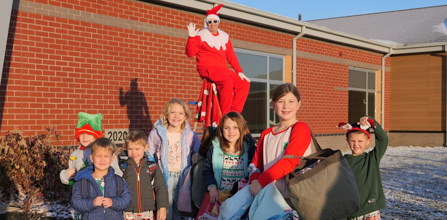 Superintendent Ryan McLane poses as an elf in front of Prairie Run Elementary with students