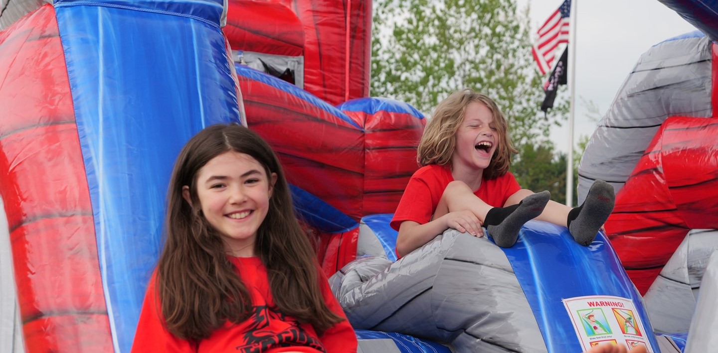 Students smile on an inflatable obstacle course